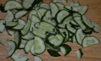 Огурцы нарежьте полукружками и также отправьте овощ в салатницу.