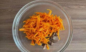 Выкладываем к субпродукту морковку по-корейски. Если ингредиент слишком длинный, то разрезаем его на небольшие кусочки.