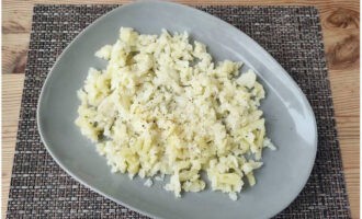 Картофель почистите, измельчите на крупной терке, выложите первым слоем на широкую салатницу и посыпьте солью с черным перцем.