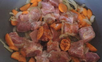 Выкладываем мясо к луку и моркови. Солим, перчим и обжариваем, пока свинина не изменится в цвете.