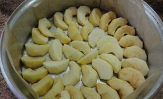 Форму для выпекания устилаем пергаментом и смазываем растительным маслом. Раскладываем яблочные дольки.
