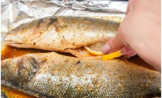 Внутрь сибаса кладем лимонные дольки. Даем рыбе напитаться специями в течение 30 минут.