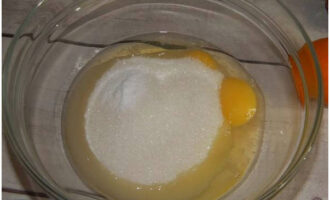 Сначала надо приготовить для торта заварной крем. В отдельную посуду разбить два куриных яйца и насыпать два вида сахара. Венчиком их взбить в однородную массу.