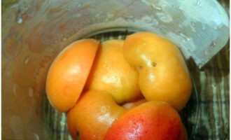 Как приготовить абрикосы без варки с сахаром на зиму? Плоды промываем под водой, разделяем на половинки и удаляем косточки. Подготовленные абрикосы кладем первым слоем в стерильные банки.