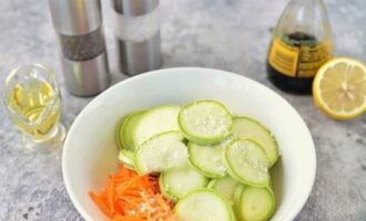 Промыв кабачки, и почистив морковку от тонкой кожуры, тонко нарезаем кабачки и измельчаем морковку в стружку на терке для корейской моркови. Выгружаем нарезку в емкость, посыпаем солью.
