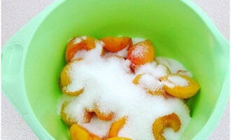 Кладем абрикосы в глубокую неокисляющуюся миску. Засыпаем их указанным количеством сахара.