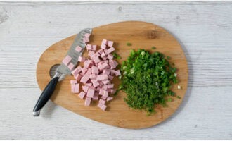 Мелкими кубиками нарезаем вареную колбасу. Измельчаем зеленый лук, петрушку и укроп.