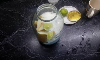 В банку кладем ломтики лайма и сахарный песок. Лайм при необходимости заменяем 0,5-1 чайной ложкой лимонки или лимоном.