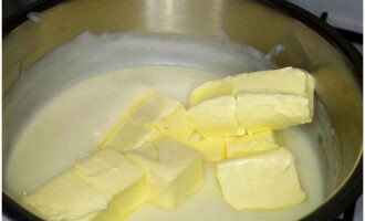 В горячий крем добавить нарезанное кусочками сливочное масло и полностью растворить. Заварной крем перелить в другую посуду и оставить для остывания.