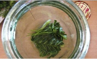 Закуска из кабачков на зиму готовится очень просто! На дно стерильной банки помещаем часть листа хрена и небольшую горсть промытой зелени.