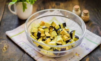 Чтобы салат с жареными баклажанами получился вкусным, надо правильно подготовить этот овощ. Баклажаны промойте, обсушите салфеткой, удалите кончики, нарежьте маленькими кубиками и переложите в отдельную посуду.