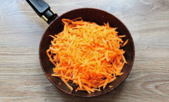 С морковки убираем кожицу, споласкиваем и измельчаем на терке с крупными отверстиями. Выкладываем в прогретую сковородку и наливаем часть растительного масла. Пассеруем до мягкости.