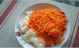 Параллельно очищаем овощи, морковь измельчаем при помощи бурачной терки, а лук произвольно нарезаем.
