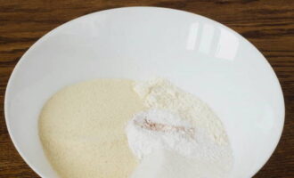 В объемной посуде объединяем просеянную муку, манную крупу, обычный и ванильный сахар, а также пекарский порошок. Хорошенько смешиваем.