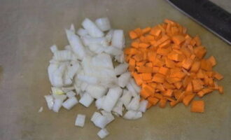 Пока варится горох, займемся овощной обжаркой. Очищаем лук и морковку. Нарезаем кубиками и припускаем на сковороде с растительным маслом. Используем половину от общего количества масла, вторую оставляем для перца.