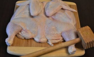 Дальше продукт аккуратно отбиваем кухонным молоточком. Чтобы не повредить кожицу цыпленка, прикройте его пленкой.