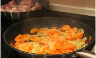 В сковороде разогреть немного растительного масла и сначала обжарить до мягкости нарезку моркови и лука.