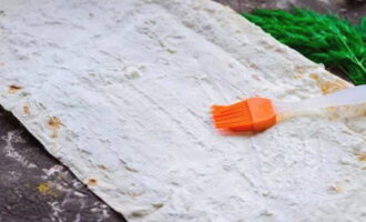 Расстилаем пласт лаваша и смазываем щедрым слоем творожного сыра.