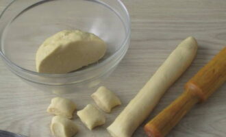 Охлажденное тесто делим пополам, одну часть скатываем в «колбаску» и нарезаем кусочками шириной не более полутора сантиметров.