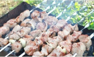 Пропитанное добавками мясо нанизываем на шампуры вместе с луком и готовим на углях.