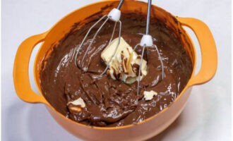 Затем в шоколадно-сливочную массу добавьте мягкое сливочное масло. Перемешивайте ганаш на низких оборотах миксера.