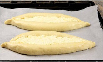 Полуфабрикаты перекладываем на противень, выстеленный пекарской бумагой. По желанию смазываем бортики желтком с водой и выпекаем 15-25 минут при температурной отметке в 200 градусов.