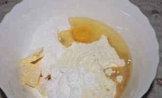 В глубокую миску просеиваем муку, отправляем куриное яйцо, размягченное сливочное масло, крахмал, сахарную пудру, соль, разрыхлитель, ванилин и растительное масло.