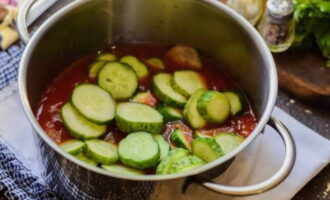 Затем в томатную заливку переложите нарезку огурцов, перемешайте и потушите ровно 5 минут от начала закипания.