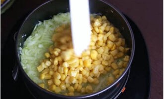 Следующим слоем уложите в кольцо натертые на терке огурцы и консервированную кукурузу. Смажьте их небольшим количеством майонеза.