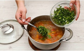 Ароматную заготовку из зелени выкладываем в суп. Солим содержимое, доводим до кипения и выключаем огонь. Закрываем блюдо крышкой и оставляем на 15 минут.