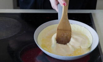 Затем наклоните сковороду на 45 градусов и лопаткой отодвиньте к центру края омлета, которые уже успели схватиться. Продолжайте помешивать омлет, пока он полностью не приготовится.