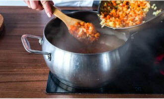 Нарезанную картошку выложите в кастрюлю с бульоном, варите 20 минут. В это время обжарьте на сковороде, на растительном масле лук и морковку, добавьте зажарку в суп за 5 минут до окончания готовки.