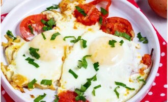 Выложите яичницу с помидорами на тарелки и посыпьте ее рубленой зеленью. Приятного аппетита!