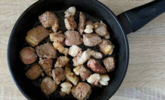 На разогретую поверхность сковороды влейте немного растительного масла и выложите кусочки говядины. Жарьте мясо, периодически помешивая, до румяной корочки.