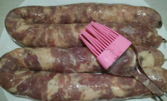 Перед запеканием наколите шкурку колбас иглой в нескольких местах, также смажьте колбаски растительным маслом.
