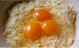 Сырные шарики легко готовятся в домашних условиях. Сыр измельчаем при помощи терки, в сырную стружку вбиваем куриные яйца.