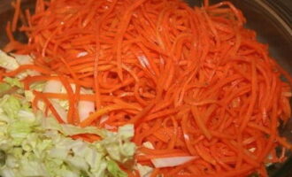 В глубокую миску отправляем капусту и добавляем к ней корейскую морковь.