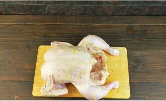 Очищенный чеснок пропускаем через чесночницу. Посыпаем курицу перцем и натираем измельченным чесноком. Отодвигая кожу на грудке, натираем филе чесноком с перцем.