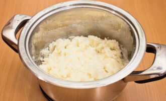 С приготовленной картошки сливаем жидкость. Разминаем картошку толкушкой до состояния пюре.