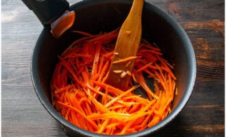 Выкладываем соломку очищенной моркови. Жарим на среднем огне около 10 минут до мягкости.