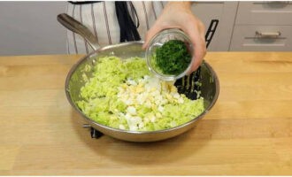 К тушеной капусте добавить мелко нарубленные отваренные яйца с зеленью, солью и перемешать.
