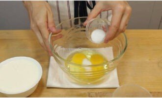 В посуду для замеса теста разбить три яйца и добавить соль с сахаром.