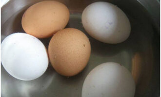 Куриные яйца отварите вкрутую. Для этого положите их в холодную воду и варите 8 минут от момента закипания.