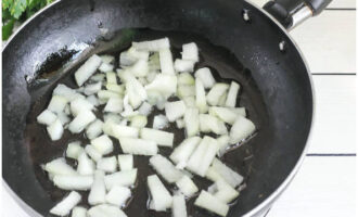 На хорошо разогретую поверхность сковороды влейте растительное масло. Сначала в течение 2-3 минут обжарьте лук, он должен стать мягким.