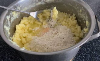 Картофельное пюре немного остудить, добавить муку, разбить яйцо и хорошо перемешать.