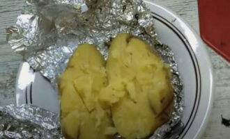Запеченный картофель, развернув фольгу сверху, разрезать пополам и мякоть немного размять вилкой.