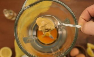В чашу блендера разбить яйца и добавить горчицу. На максимальной скорости их взбить в однородную массу.