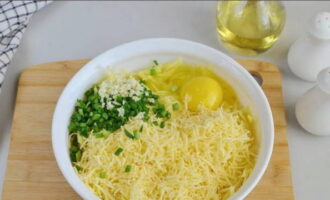 К полученной массе разбиваем яйцо, добавляем натертый на терке сыр, чеснок и рубленые перья зеленого лука.