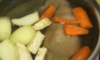 Сюда же отправляем лук, морковь и корень петрушки. Всыпаем соль и варим около трех часов.
