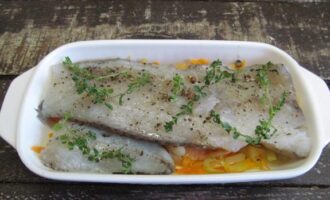 На жареные овощи расположите филе минтая, на рыбу также положите несколько веточек свежего тимьяна.